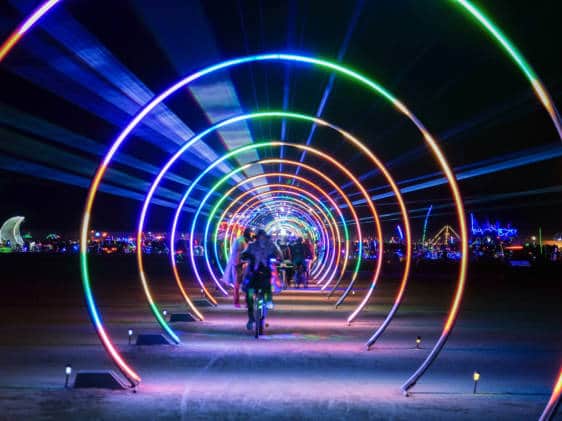 People walking under a multi-coloured light installation
